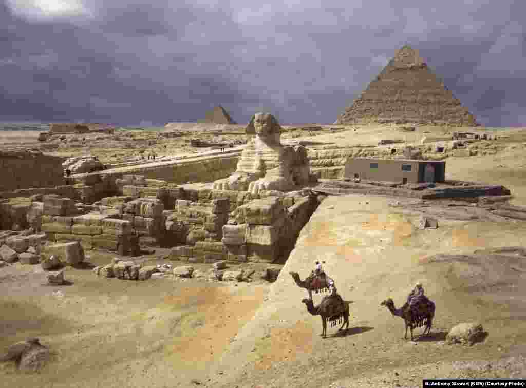 Three figures on camelback behold the pyramids of Giza in 1938.