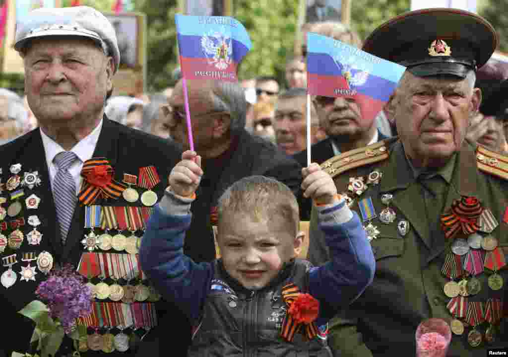 A child holds flags saying "Luhansk Republic" as he celebrates Victory Day with former Soviet servicemen during celebrations in the eastern Ukrainian city of Luhansk on May 9. (Reuters/Valentyn Ogirenko)
