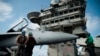 AT SEA -- A pilot speaks to a crew member by an F/A-18 fighter jet on the deck of the USS Abraham Lincoln aircraft carrier in the Arabian Sea, June 3, 2019