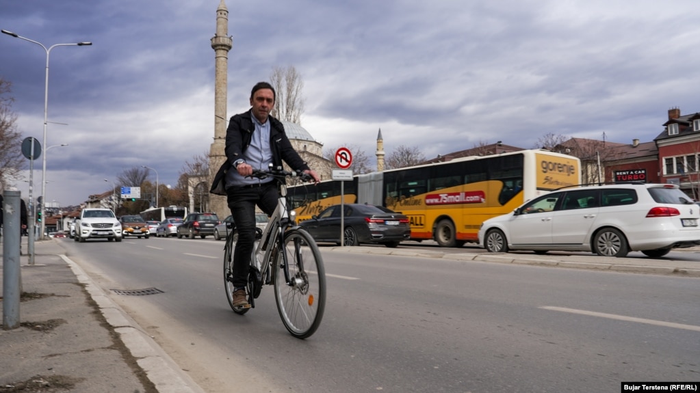 Një person shihet duke kaluar nëpër një rrugë afër ndërtesës së Kuvendit të Kosovës. Në këtë pjesë, siç mund të vërehet edhe në fotografi, nuk ka shtigje të dedikuar për biçikleta dhe ata që përdorin këtë mjet transporti detyrohen të kalojnë nëpër rrugët e mbushura me vetura. Nga Komuna e Prishtinës nuk janë përgjigjur se sa saktësisht ka shtigje biçikletash kryeqyteti.