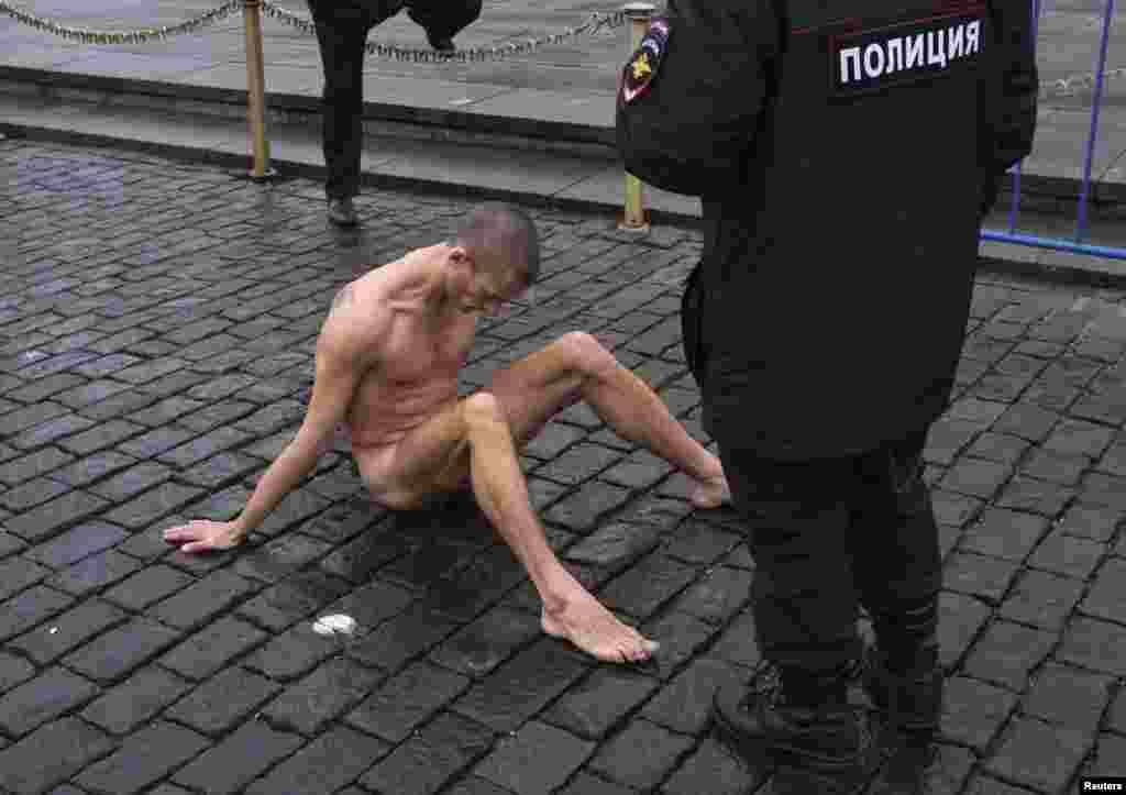 Moscow police approach artist Pyotr Pavlensky on Red Square after he nailed himself to the pavestones by his genitals as part of an art performance in protest of what he sees as apathy in contemporary Russian society and the possibility such indifference can lead eventually to a police state. (Reuters/Maksim Zmeyev)