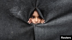 Raseljeno palestinsko dijete gleda kroz zaklon napravljen od ćebadi u školi koju vodi UNRWA nakon što je američki predsjednik Donald Trump objavio da su se Izrael i Hamas složili oko prve faze primirja u Gazi, Han Junis na jugu Pojasa Gaze, 9. oktobar 2025. 