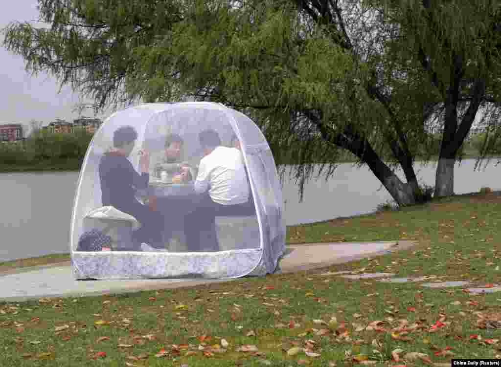 People enjoy a meal inside a tent to protect themselves from the coronavirus at a park in Nanjing, Jiangsu Province, China. (Reuters/China Daily)