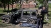 Поліцейський стоїть біля автівки, пошкодженої внаслідок російського обстрілу, Золочів, 1 травня 2023 року 