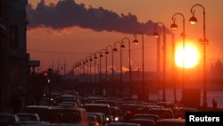 Russia -- Pipes of a thermal power plant are seen during sunset, with cars stuck in a traffic jam in the foreground, in St. Petersburg, 15Feb2011