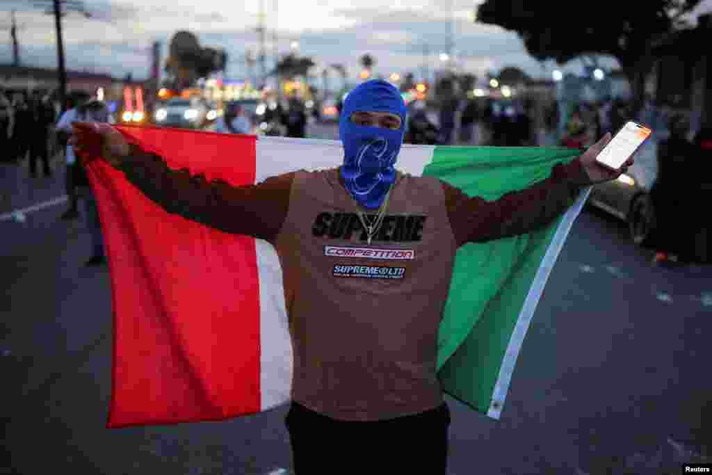 Протестующий держит мексиканский флаг во время противостояния между полицией и протестующими после многочисленных задержаний сотрудниками Иммиграционной и таможенной службы (ICE) в городе Парамаунт округа Лос-Анджелес, Калифорния, США, 7 июня 2025 года. REUTERS/Daniel Cole