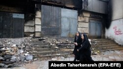 Ирандык аялдар талкаланган «Мелат» банкынын алдынан өтүп баратышат. 20-ноябрь, 2019-жыл.