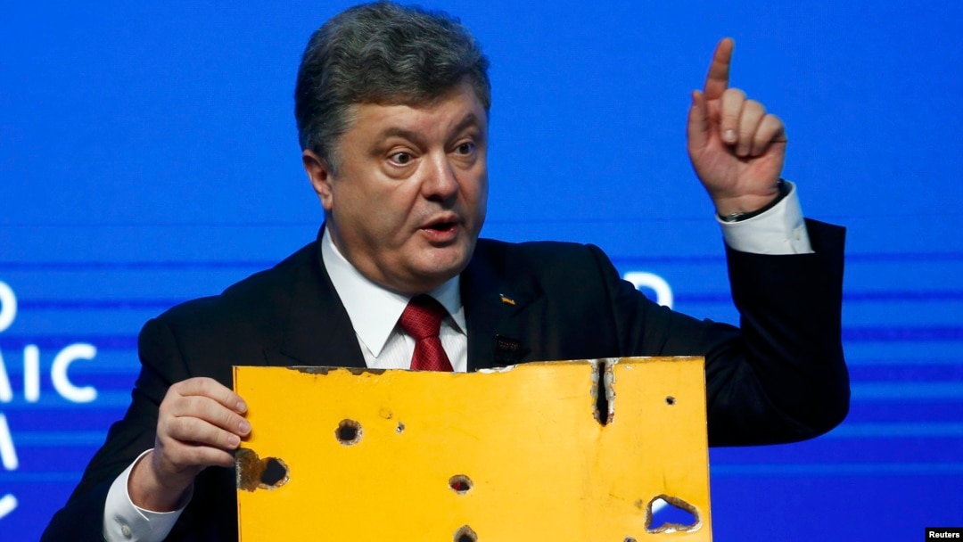 Ukrainian President Petro Poroshenko holds a fragment of a bus body that he says shows a Russian missile attack on a civilian bus as he addresses The Future of Ukraine event in the Swiss mountain resort of Davos on January 21.