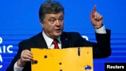 Ukrainian President Petro Poroshenko holds a fragment of a bus body that he says shows a Russian missile attack on a civilian bus as he addresses The Future of Ukraine event in the Swiss mountain resort of Davos on January 21.