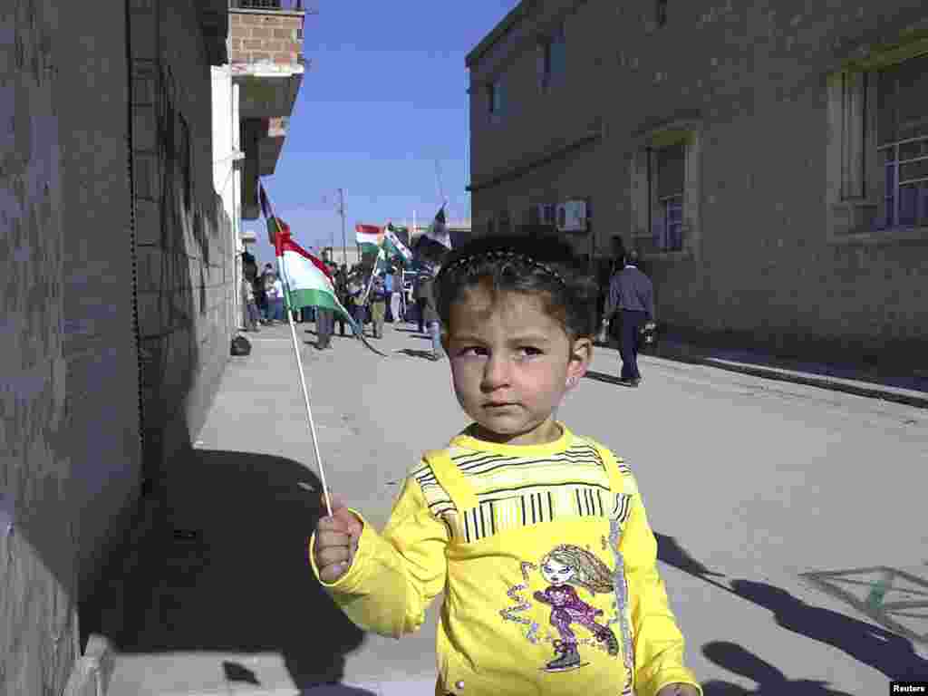 A Syrian girl holds a Kurdish flag during an antigovernment demonstration in the town of Amude on December 6. (Photo by Reuters)