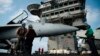 A pilot speaks to a crew member by an F/A-18 fighter jet on the deck of the USS Abraham Lincoln aircraft carrier in the Arabian Sea, June 3, 2019