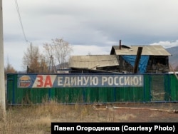 Лозунг на фоне разваливающегося дома в посёлке Усть-Омчуг
