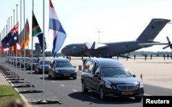 A convoy of hearses with the remains of the victims of MH17 drives past international flags as it leaves Eindhoven airport to a military base in Hilversum, Netherlands, on July 23, 2014.