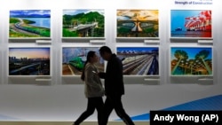 People walk by a display board showcasing China's construction projects at the media center of the Belt and Road Initiative in Beijing. (file photo)