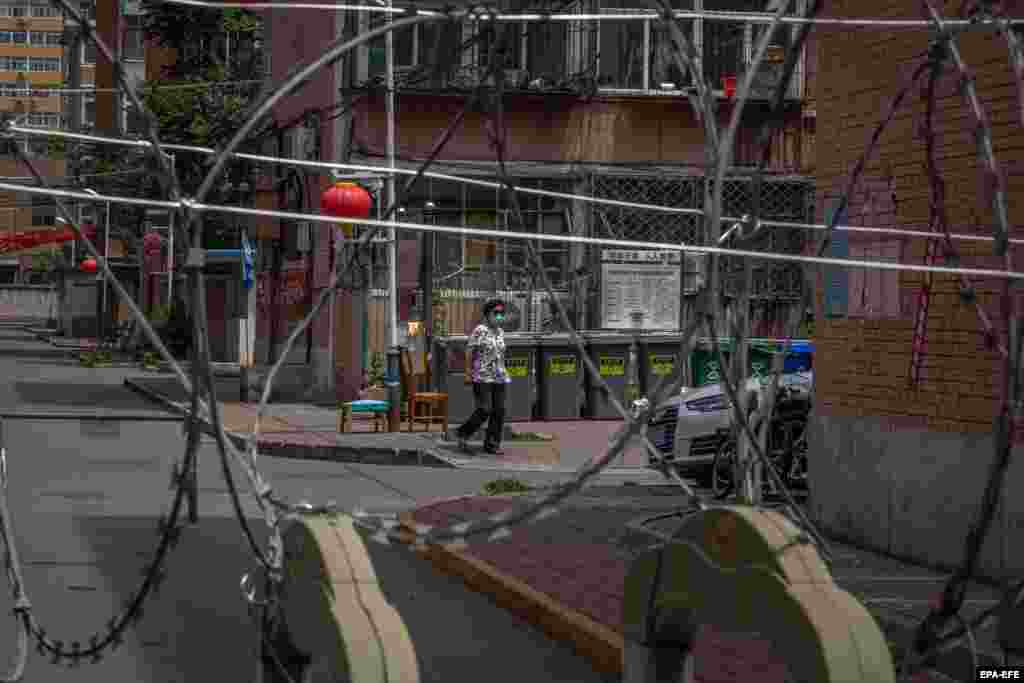 Жінка &ndash; в захисній масці для обличчя &ndash; гуляє біля заблокованого житлового комплексу поблизу ринку Юквандон, в районі Гайдян, Пекін, Китай