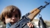 A boy holds a weapon as he stands with armed tribesmen loyal to the Houthi movement during a rally held to mobilize fighters for the battles against government forces, in Sanaa. File photo