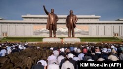 În fața statuilor lui Kim Ir Sen și Kim Jong Il, o mare de oameni aducându-și omagiile cu ocazia cele de-a 25-a comemorări a morții lui Kim Ir Sen, pe dealul Mansu în Phenian în 8 iulie 2019 (Kim Won Jin / AFP)