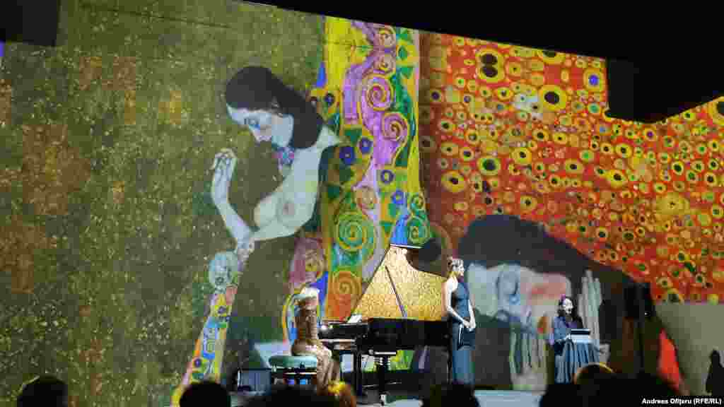 Muzeul de Artă Imersivă din București - adică locul unde cu ajutorul tehnologiei poți intra senzorial într-o operă de artă - a fost invitat și el în dansul urban al Festivalului Enescu. A făcut-o inclusiv cu o partitură dublu-vieneză: Maestrul artei decorative expandate în marea pictură, Gustav Klimt, plus un pian Bosendorfer/ Yamaha, activat de Alexandra Silocea și acordurile „Ver Sacrum”.