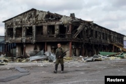 Пророссийский боевик идет у здания разрушенного из-за боёв здания фабрики. Нижняя Кринка, 23 сентября 2014 года.