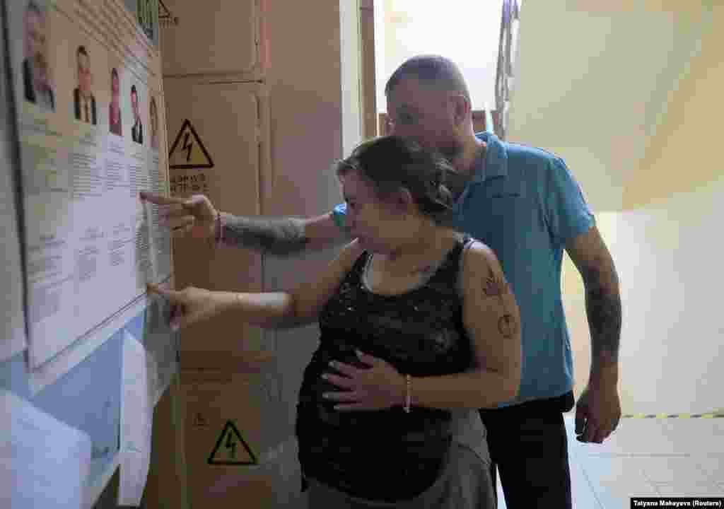 Voters study a candidate information board at a polling station in Moscow.