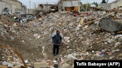 Мужчина стоит среди обломков разрушенного дома, пострадавшего от ракетного удара во время продолжающегося военного конфликта между Арменией и Азербайджаном из-за отколовшегося региона Нагорный Карабах, в жилом районе Гянджа, 21 октября 2020 года.