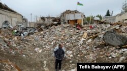 Мужчина стоит среди обломков разрушенного дома, пострадавшего от ракетного удара во время продолжающегося военного конфликта между Арменией и Азербайджаном из-за отколовшегося региона Нагорный Карабах, в жилом районе Гянджа, 21 октября 2020 года.