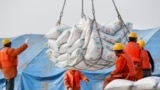 CHINA -- Workers transport imported soybean products at a port in Nantong, Jiangsu province, March 22, 2018