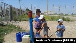 Дети набирают воду из колонки на окраине поселка Ондирис. Астана, 24 июня 2014 года. 