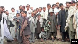 Local residents stand near the crater formed by one of the explosions in Kandahar on April 26.