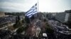 A huge flag of Greece flies over people demonstrating to urge the government not to compromise in the festering name row with neighboring Macedonia in Athens on February 4. (AFP/Louisa Gouliamaki)