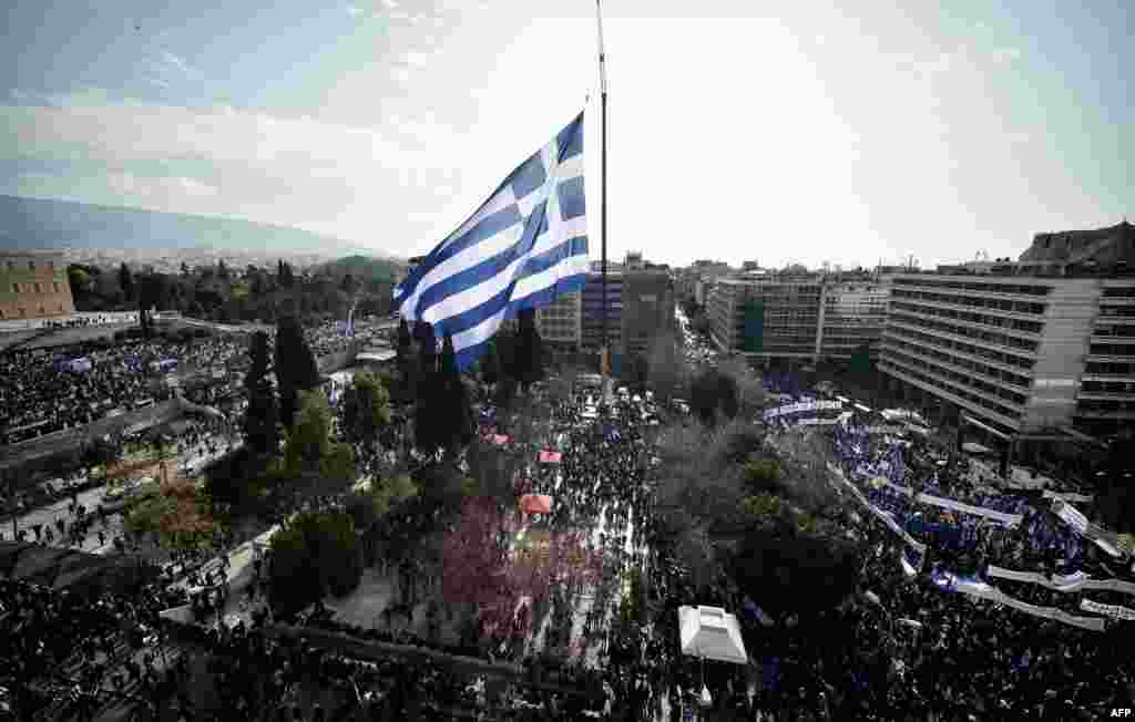 A huge flag of Greece flies over people demonstrating to urge the government not to compromise in the festering name row with neighboring Macedonia in Athens on February 4. (AFP/Louisa Gouliamaki)