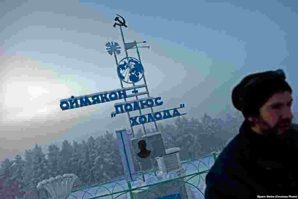 A visitor at &quot;The Pole of Cold&quot; marker in the village of Oymyakon