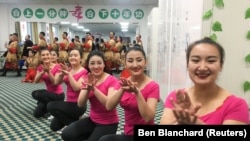 Резидентки «центра профессионального образования», предположительно уйгурки, танцуют перед журналистами во время их официального визита, организованного китайскими властями в уезде Хотан, Синьцзян-Уйгурский автономный район, Китай. 5 января 2019 года. 