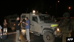 Jewish settlers stop at an Israeli army roadblock that leads to the West Bank village of Bani Nai, where four Israelis were gunned down on August 31.
