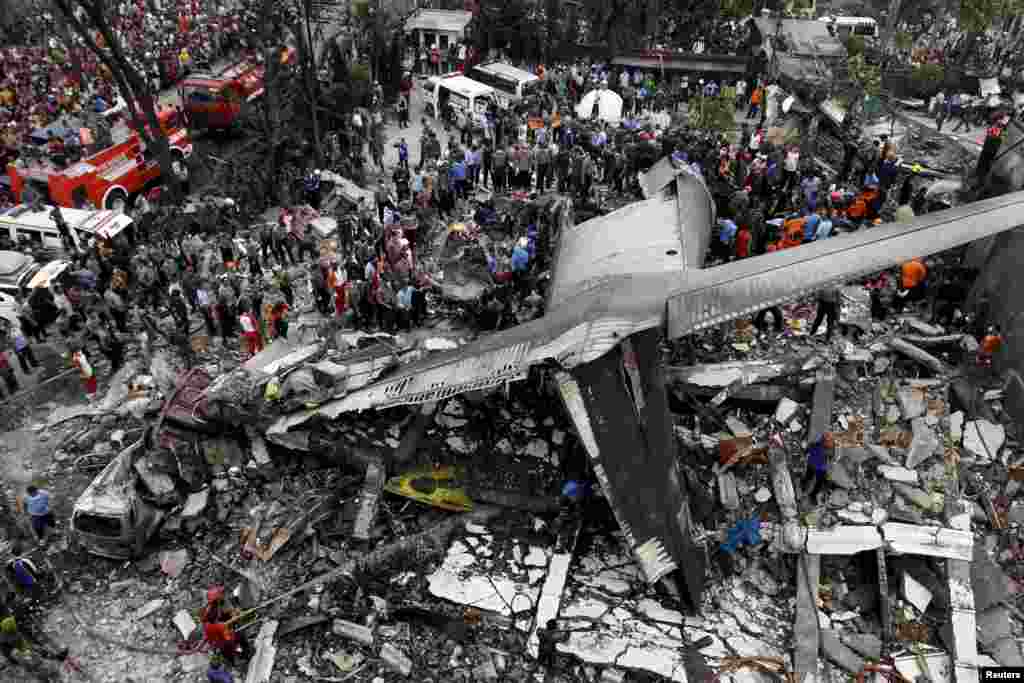 Security forces and rescue teams examine the wreckage of an Indonesian military C-130 Hercules transport plane after it crashed into a residential area in the North Sumatra city of Medan in Indonesia, on June 30, 2015. (Reuters/Roni Bintang) 