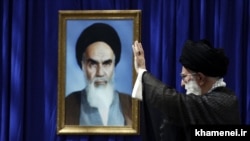 Iran -- Iran's Supreme Leader Ali Khamenei before a portrait of his predecessor Ayatollah Ruhollah Khomeini, undated.