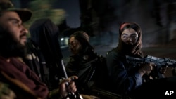 Taliban fighters ride in the back of a vehicle during a night patrol in Kabul.