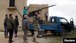 A rebel fighter from the Ahrar al-Sham Islamist movement gestures while standing on a pick-up truck mounted with an antiaircraft weapon, as he looks at the sky with his fellow fighters outside Idlib.
