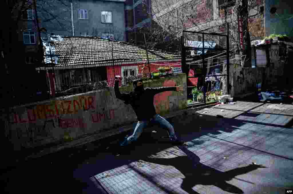 A protester throws a stone towards Turkish antiriot police in Istanbul as people gather to mark the second anniversary of the death of the youngest victim of the Gezi Park protests on March 11. (AFP/Ozan Kose)