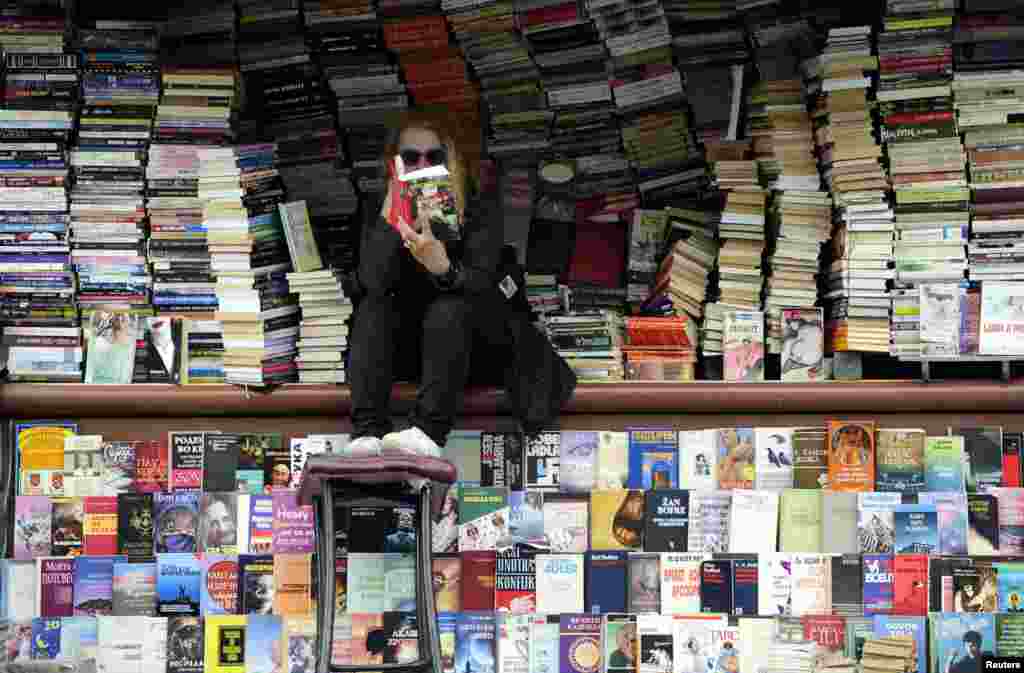 A woman reads at her open air book store in the Macedonian capital, Skopje, on April 24. (Reuters/Ognen Teofilovski)