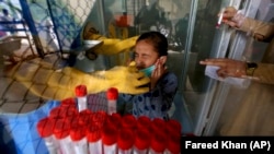 A young girl reacts while having a nasal swab sample taken by a health worker at a COVID-19 testing facility at a hospital in Karachi on March 18.