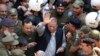 Police escort jailed former Pakistani prime minister Nawaz Sharif (C) as he leaves the accountability court in Lahore on October 11.