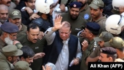 Police escort jailed former Pakistani prime minister Nawaz Sharif (C) as he leaves the accountability court in Lahore on October 11.