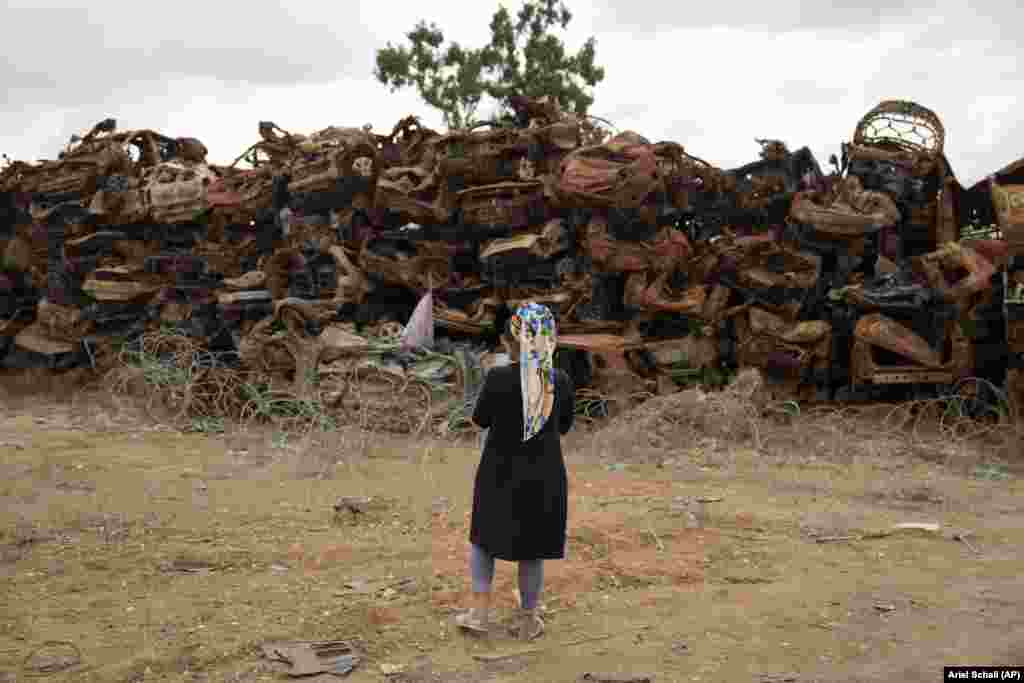  A woman looks at charred vehicles burned in the October 7, 2023, cross-border attack by Hamas militants outside the town of Netivot, southern Israel. &nbsp; 