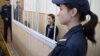 Olga Stepanova is seen in the defendant's cage in a courtroom in Vitsebsk.