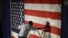 Hotel employee Denzil Telphia of Boston steams the wrinkles from an American flag hanging as a backdrop at the election night party for Democrat Elizabeth Warren, who won a seat in the U.S. Senate.