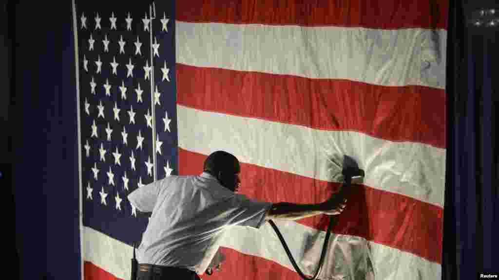 Hotel employee Denzil Telphia of Boston steams the wrinkles from an American flag hanging as a backdrop at the election night party for Democrat Elizabeth Warren, who won a seat in the U.S. Senate.