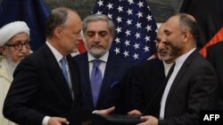 Afghan National Security Adviser Hanif Atmar (R) and US Ambassador to Afghanistan James Cunningham (2L) hold their documents after signing a deal September, 2014.