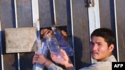 An Afghan man takes empty water bottles from Afghan men in Iranian detention in the southeastern Iranian city of Zahedan (file photo). Afghan officials say more than 5,600 Afghan nationals are in Iranian prisons for alleged drug crimes.