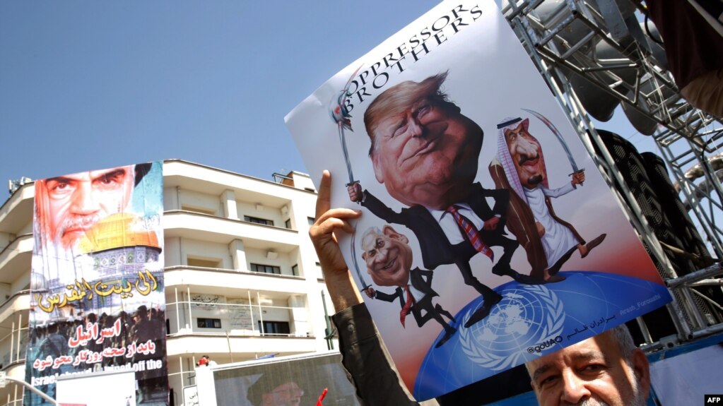An Iranian man holds a poster bearing images of Israeli Prime Minister Benjamin Netanyahu, US President Donald Trump and Saudi King Salam during a parade marking al-Quds (Jerusalem) day in Tehran, June 23, 2017